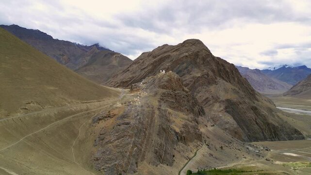 Aerial view of the rugged Zanskar valley landscape with winding mountain paths and rocky terrain under a cloudy sky in Zanskar, Ladakh, India.