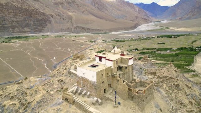Aerial view of the ancient monastery perched on a rocky hill in the Zanskar valley, surrounded by arid mountain landscapes and a winding river in Zanskar, Ladakh, India.