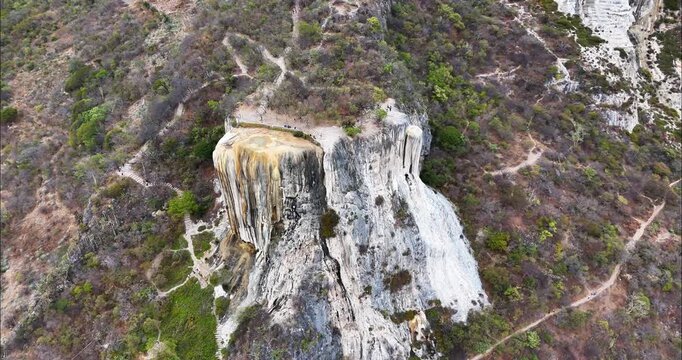 Aerial view of the petrified waterfalls at Hierve el Agua with rugged cliffs and hiking trails in the surrounding landscape in Oaxaca de Juarez, Oaxaca, Mexico.