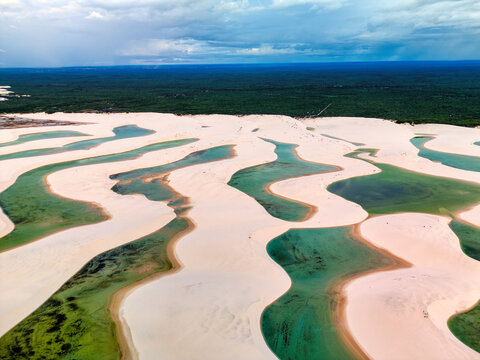 Aerial view of Lagoa Bonita with its iconic white sand dunes and crystal clear turquoise rainwater lagoons surrounded by lush vegetation in Barreirinhas, State of Maranhao, Brazil.
