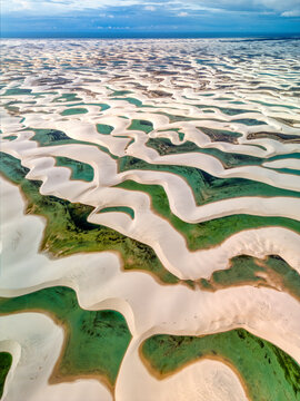 Aerial view of Lagoa Bonita, featuring vast white sand dunes interspersed with vibrant green rainwater lagoons in Barreirinhas, State of Maranhao, Brazil.