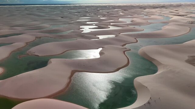 Aerial view of the white sand dunes and turquoise lagoons of Parque Nacional dos Lencois Maranhenses in MA, Brazil.