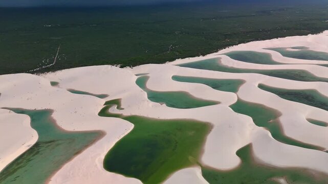 Aerial view of white sand dunes and turquoise lagoons in Parque Nacional dos Lencois Maranhenses, MA, Brazil.