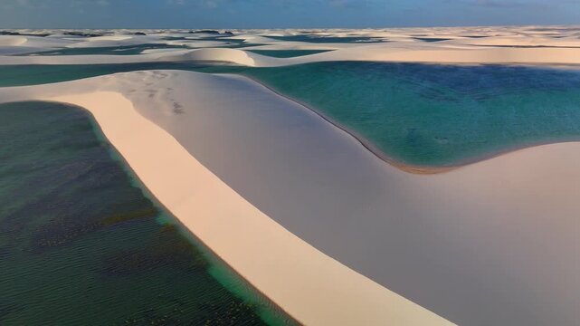 Aerial view of white sand dunes and turquoise lagoons in Parque Nacional dos Lencois Maranhenses, MA, Brazil.