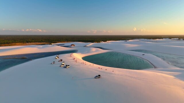 Aerial view of Parque Nacional dos Lencois Maranhenses with white sand dunes and turquoise lagoons under golden hour light in MA, Brazil.