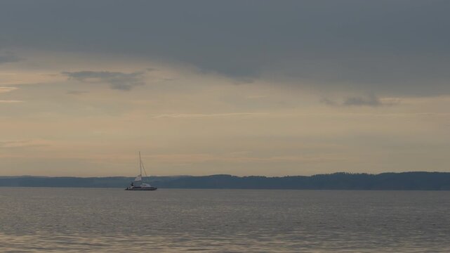 Sailing boat moves on the lake with during sunset