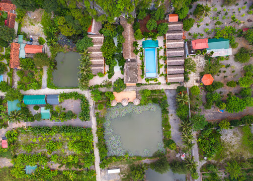 Aerial view of the Tam Coc - Bich Dong resort with a swimming pool, lotus ponds, and lush gardens set amidst limestone karst formations in Nam Hoa Lu, Ninh Binh, Vietnam.