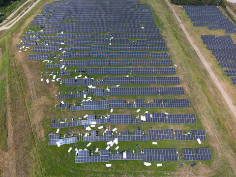 Aerial view of a solar farm with damaged and shattered photovoltaic panels scattered across the green field in Crescentino, Piedmont, Italy.