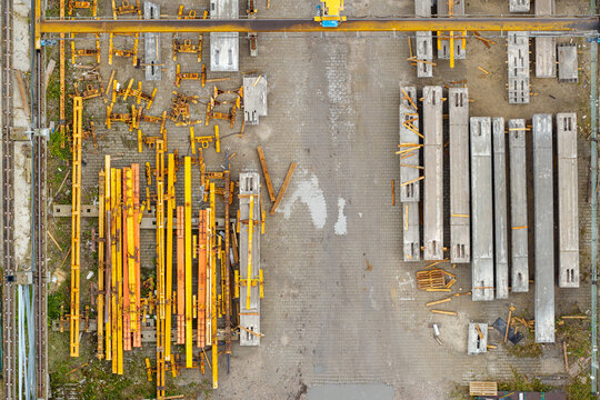 Aerial view of prestressed concrete elements and yellow metal construction frames arranged in a storage yard in Poland.