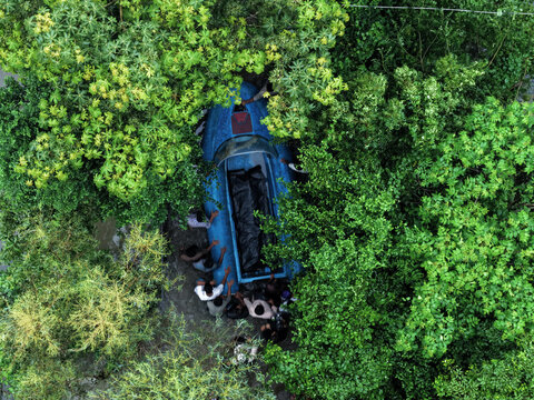 Banshkhali Upazila, Bangladesh - 10 July 2026: Aerial view of a blue boat surrounded by dense green foliage with people gathered nearby.