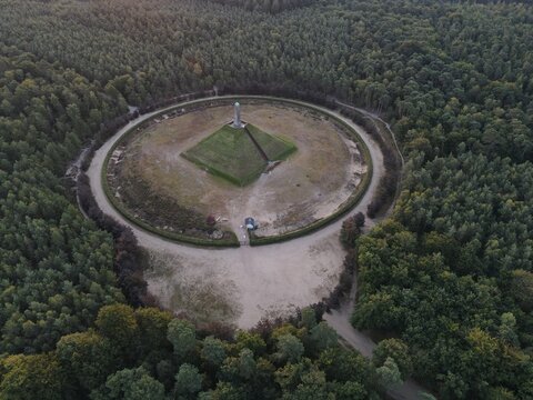 Netherlands - 12 July 2026: Aerial view of the Pyramid of Austerlitz, a historic monument with a stone obelisk at its peak, situated in a circular clearing surrounded by forest.