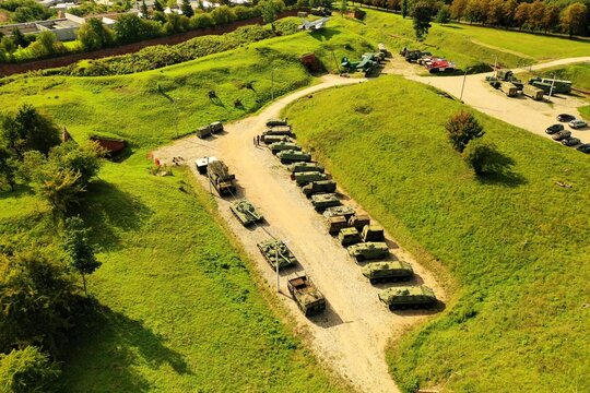 Aerial view of a collection of military tanks and armored vehicles displayed on the grassy grounds of the Ninth Fort museum in Kaunas, Kaunas County, Lithuania.
