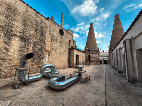 Seville, Spain - 02 November 2025: View of the historic Centro Ceramica Triana with its iconic brick kilns, metal ventilation ducts, and stone courtyard under a blue sky.