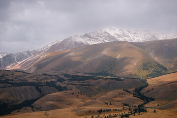 Obraz premium Majestic mountain landscape with snow-capped peaks and rolling hills