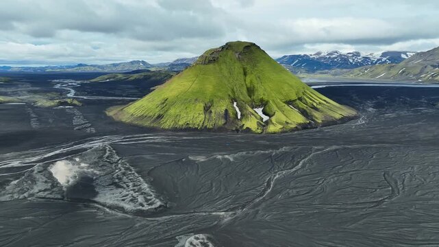 Aerial view of Maelifell volcano, a moss-covered cone rising from black volcanic sand, surrounded by vast lava fields in Kirkjubaejarklaustur, Skaftarhreppur, Iceland.