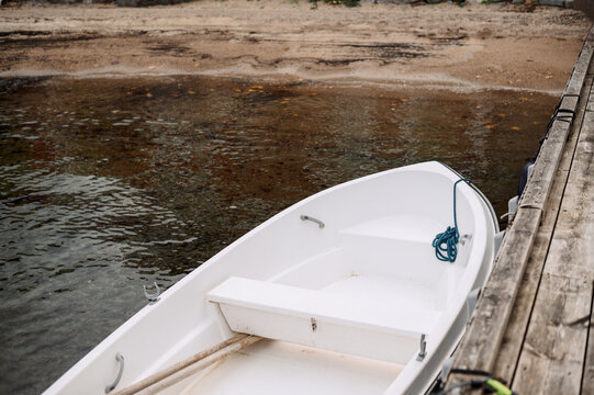 White rowboat tied to a wooden pier on a calm Norwegian fjord