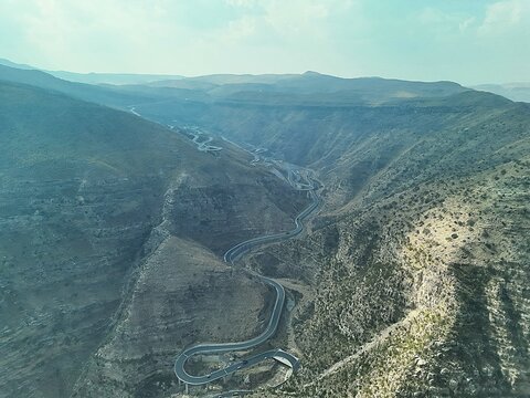 Aerial view of the winding road and steel bridge at Fort Munro surrounded by steep rocky mountain slopes and rugged terrain in Dera Ghazi Khan, Punjab, Pakistan.
