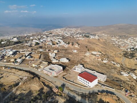 Aerial view of Fort Munro hill station featuring scattered residential buildings, winding roads, and dry mountainous terrain in Dera Ghazi Khan, Punjab, Pakistan.