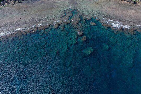 Aerial view of the turquoise coral reef and clear blue waters surrounding the coastline of Miyakojima, Okinawa, Japan.