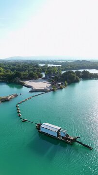 Aerial view of the Areeiras da Limia sand extraction site featuring turquoise water and floating dredging equipment surrounded by lush greenery in Ourense, Ourense, Spain.