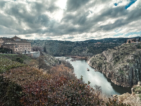Toledo, Castile-La Mancha, Spain - 27 December 2025: View of the historic city of Toledo overlooking the Tagus River flowing through a deep rocky gorge under a dramatic cloudy sky.