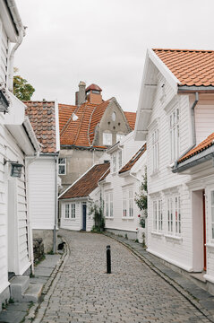 Charming white wooden houses line a cobblestone street in Norway