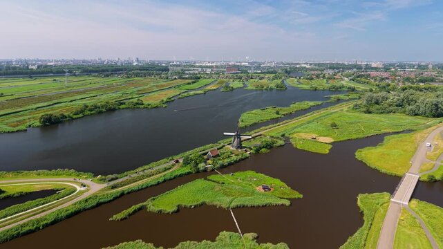 Aerial view of a historic windmill surrounded by lush green fields and waterways in the rural landscape of Amsterdam, North Holland, Netherlands.