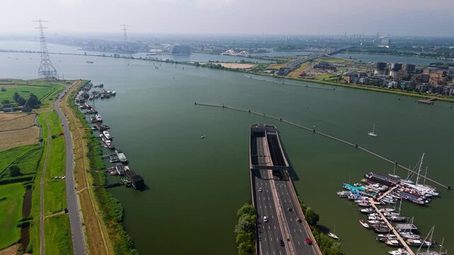 Aerial view of the Zeeburgertunnel entrance with traffic flowing alongside a marina filled with boats on the IJ river in Amsterdam, North Holland, Netherlands.
