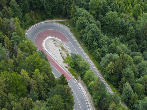 Aerial view of a sharp hairpin turn on a mountain road winding through a dense green forest in Slovakia.