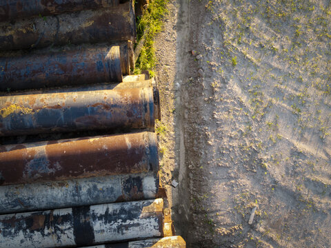 Aerial view of rusted metal pipes stacked on the ground beside a dirt path, Krakow, Lesser Poland Voivode, Poland.