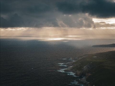 Aerial view of Stony Hill with dramatic dark clouds, sunbeams breaking through, and rugged cliffs meeting the Southern Ocean in Torndirrup, Western Australia, Australia.