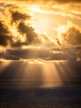 Aerial view of Stony Hill overlooking the ocean at sunset with dramatic sun rays breaking through clouds over the water in Torndirrup, Western Australia, Australia.
