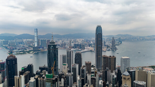 Hong Kong, Hong Kong - 12 July 2026: Aerial view of the dense Hong Kong skyline with towering skyscrapers overlooking Victoria Harbour under a cloudy sky.