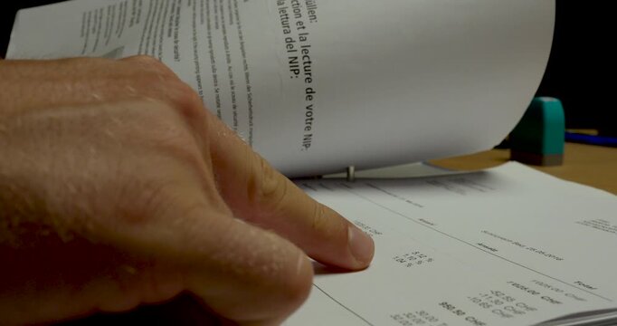 Close-up of a person flipping through documents stored in a ring binder. Ideal for document review, office administration, filing, record keeping, and business organization concepts.