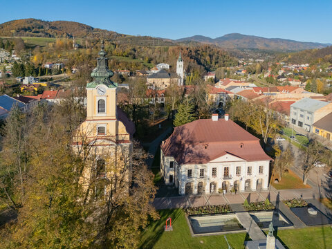 Aerial view of the Parish Church of the Assumption of the Virgin Mary with its yellow tower and adjacent historic building in Brezno, Banska Bystrica Regio, Slovakia.