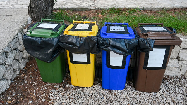 Outdoor recycling and waste collection bins lined up for sorted waste disposal. Row of colorful municipal waste containers for sorted rubbish management.