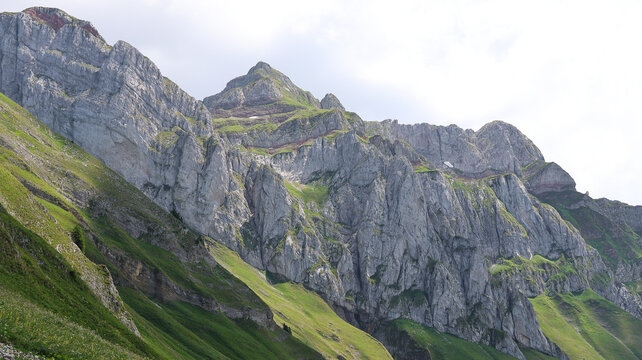 View of Cornettes de Bise mountain range with rugged limestone peaks, steep green grassy slopes, and rocky cliffs in La Chapelle-d'Abondance, Auvergne-Rhone-Alpes, France.