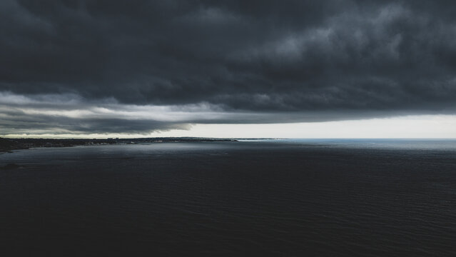 Aerial view of dark stormy clouds hanging over the sea and the rugged coastline of Japan.