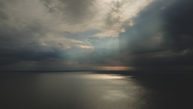 Aerial view of the vast ocean under a dramatic cloudy sky with sunbeams breaking through the clouds in Japan.