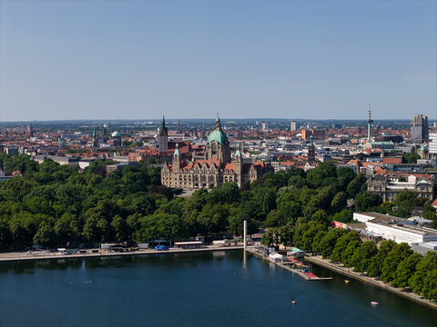 Hanover, Germany - 12 July 2026: Aerial view of Maschsee and the New Town Hall surrounded by lush green trees and urban architecture under a clear blue sky.