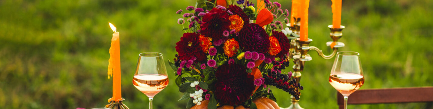 Banner. Garden romantic party outside with wine, cheese, fruits. Field or meadow, family event, cozy autumn atmosphere, fall vibes. Wooden furniture, pumpkin with flowers as centrepiece, fresh dahlia