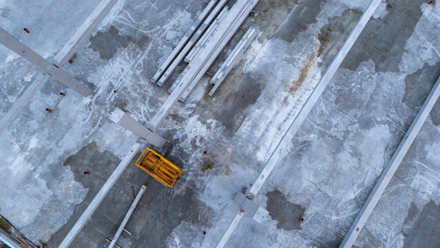 Aerial view of a construction site featuring concrete beams and a yellow cart on a concrete floor in Gdansk, Pomeranian Voivodeship, Poland.