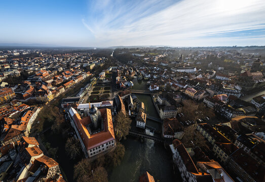 Aerial view of the historic old town of Bamberg with the Altes Rathaus on the Regnitz river, red-tiled rooftops, and winding streets under a bright sky Bamberg, Bavaria, Germany.