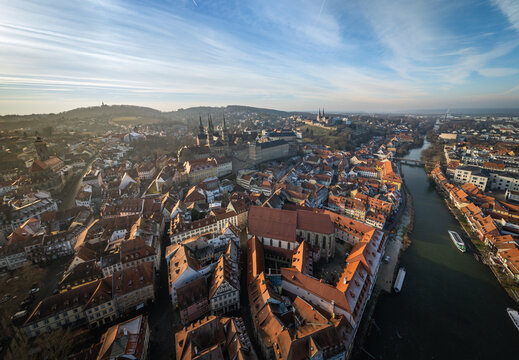 Aerial view of the historic old town of Bamberg with its iconic red-tiled rooftops, the winding Regnitz river, and the cathedral under a clear blue sky in Bamberg, Bavaria, Germany.