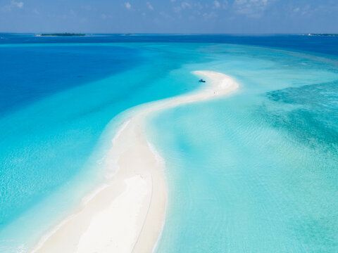 Aerial view of the white sandbank surrounded by vibrant turquoise waters and coral reefs in Dhonfanu, Baa Atoll, Maldives.