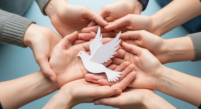 Many hands holding a paper dove representing peace, unity, and cooperation