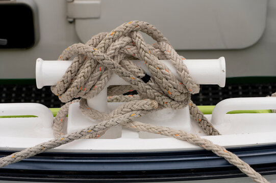 Mooring rope tied around boat cleat on vessel deck close up