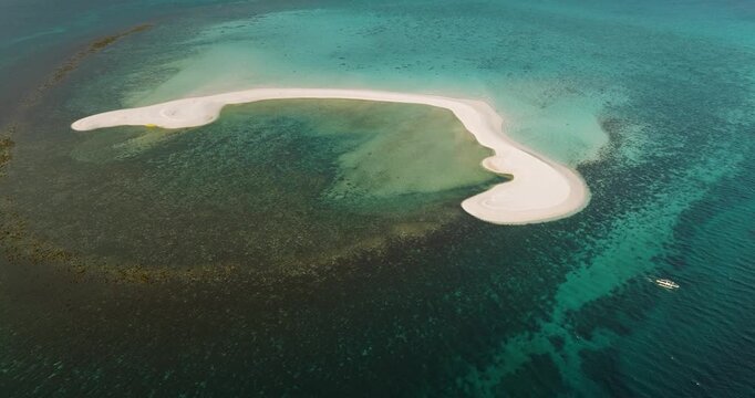 Aerial view of White Island sandbar surrounded by turquoise waters and coral reefs with a small boat nearby in Mambajao, Camiguin, Philippines.