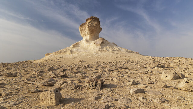 View of Zekreet Rock Formation rising from the arid desert landscape under a clear blue sky with scattered rocks in the foreground Zekreet, Al Sheehaniya Municipality, Qatar.
