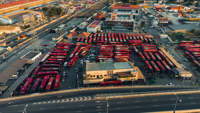 Aerial view of the VIP Bus Station in Accra, featuring rows of parked red buses, terminal buildings, and surrounding urban infrastructure in Accra, Greater Accra Region, Ghana.